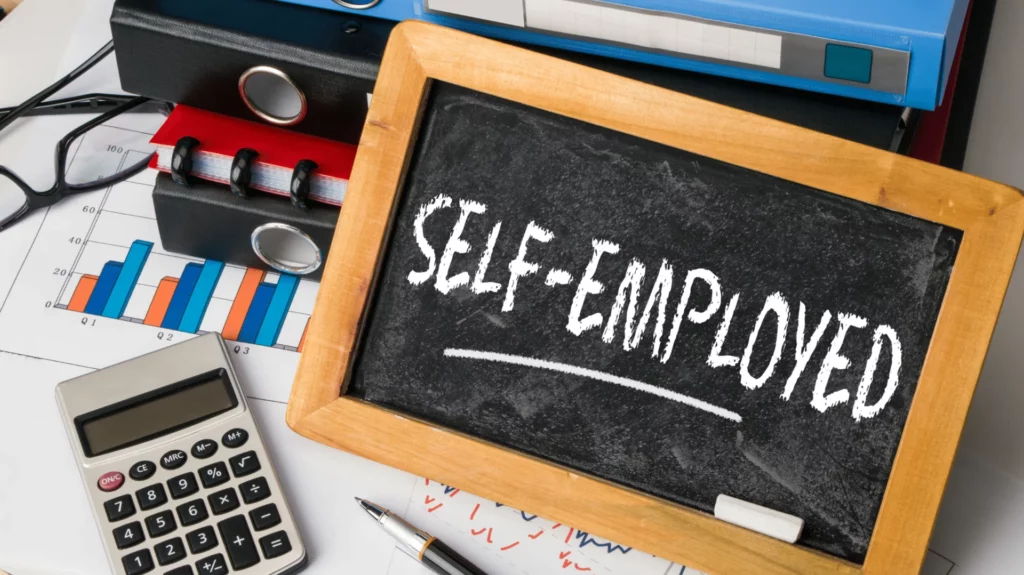 image depicting self employed financing with a calculator and board with the words "self-employed" written on it.